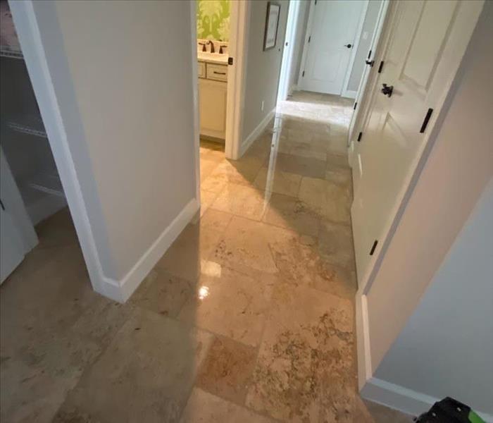 Hallway with tile floor and standing water by SERVPRO equipment