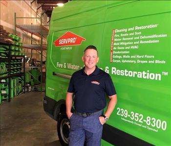 male employee in black shirt in front of green van