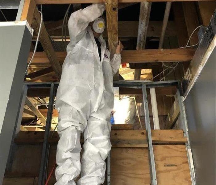 male in white protective suit Wiping Soot Off Wood Surfaces